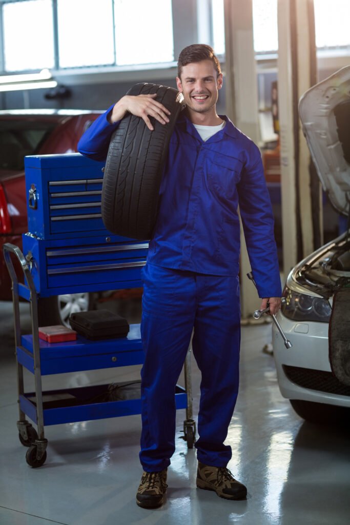 portrait of mechanic carrying a tyre