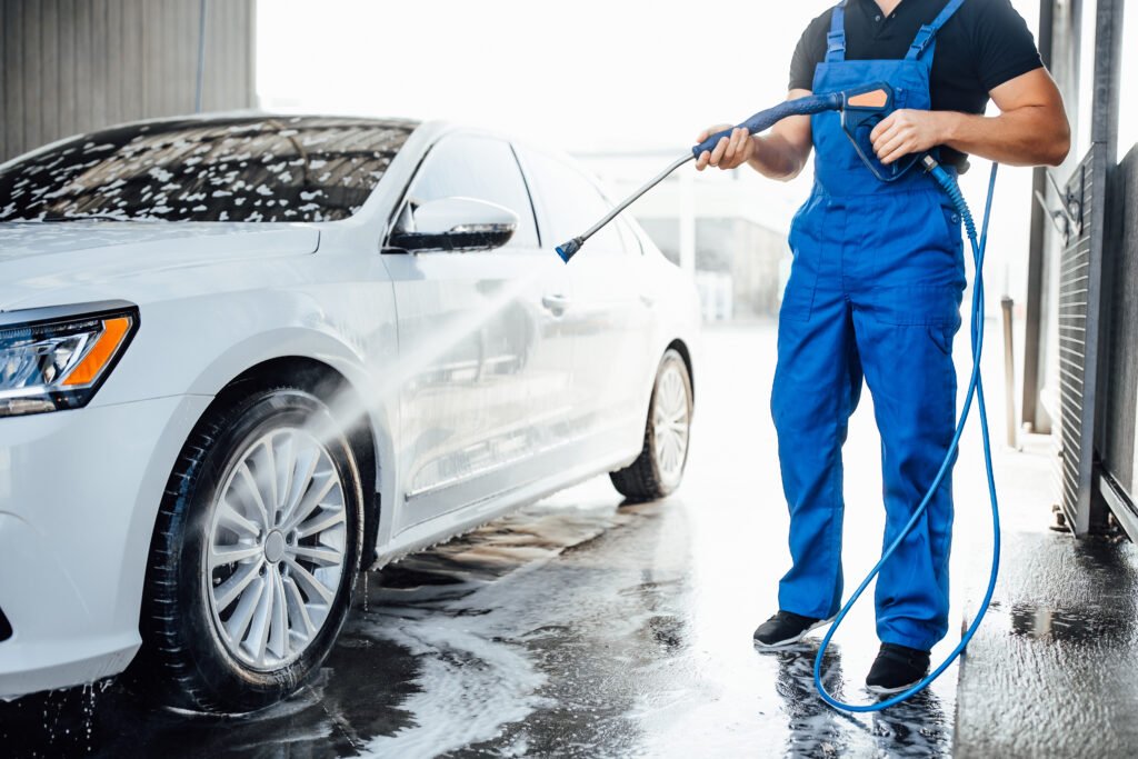 professional washer blue uniform washing luxury car with water gun open air car wash