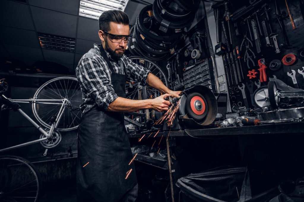attractive man is working with machine at busy bicycle workshop.